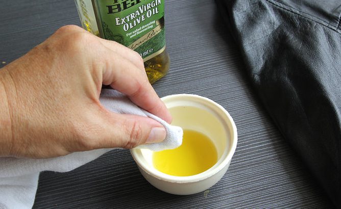 Dùng khăn mềm thấm dầu ô liu giặt để àm sạch áo da