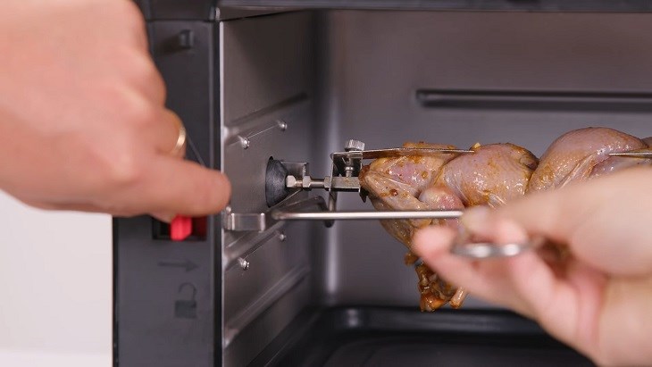 Nút khóa màu đỏ bên hông lò chiên Hawonkoo AFH 100 để giữ chắc xiên quay.