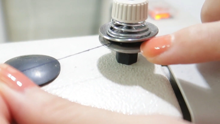 Mắc chỉ qua phía giữa 2 đồng tiền phía trên máy