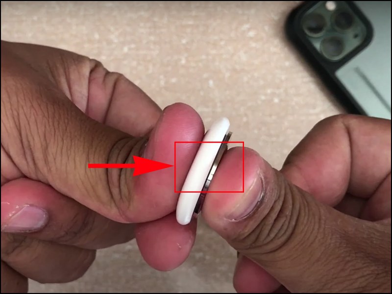 Dùng ngón tay ấn và xoay ngược chiều kim đồng hồ để tháo nắp AirTag