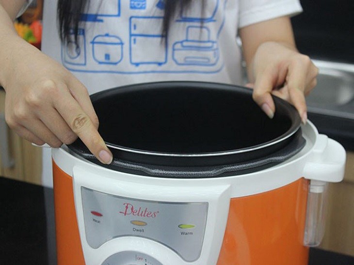 Bạn nên dùng cả hai tay để đặt lòng nồi vào bên trong nồi cơm điện